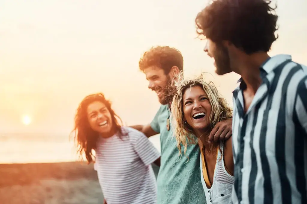 4 friends laughing walking on beach